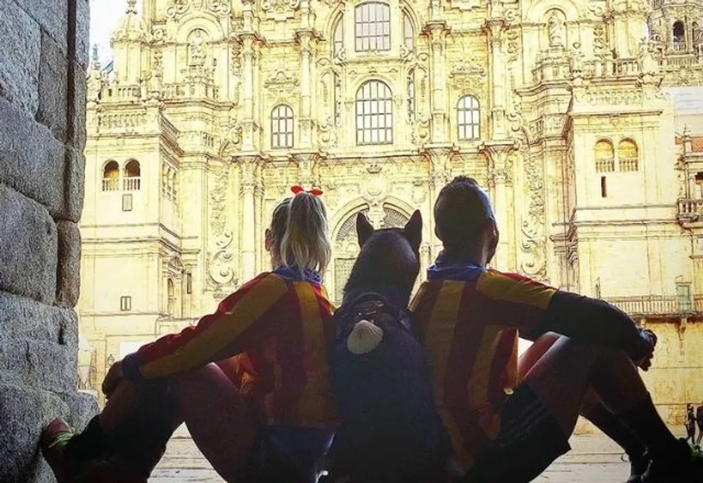 Dos peregrinos con su perro en la plaza del Obradoiro
