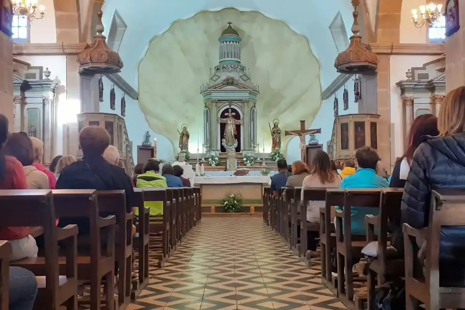 Peregrinos asistiendo a una misa en Semana Santa en la iglesia de Santaia de O Pino, en el Camino Francés