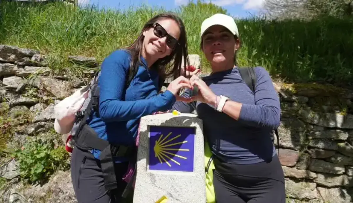 Peregrinas en un mojón posando a cámara 