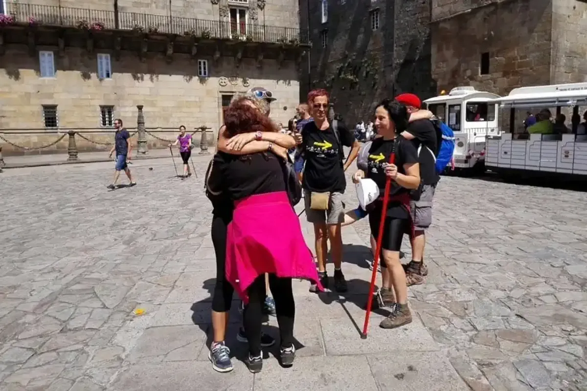 Peregrinos de un grupo organizado que se abrazan al llegar a la Plaza del Obradoiro en Santiago de Compostela, final del Camino