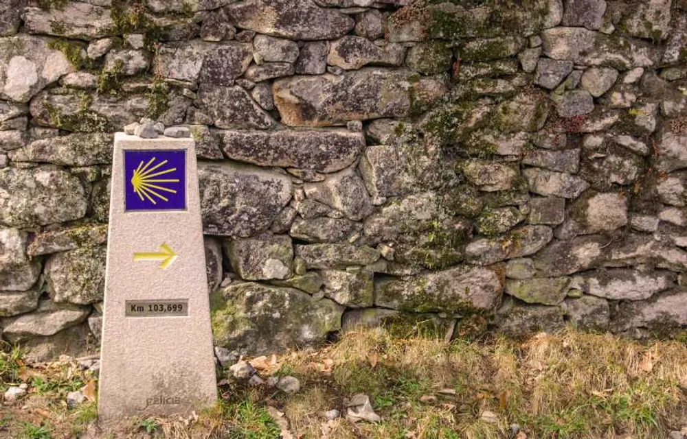 Muro de piedra y un hito del Camino