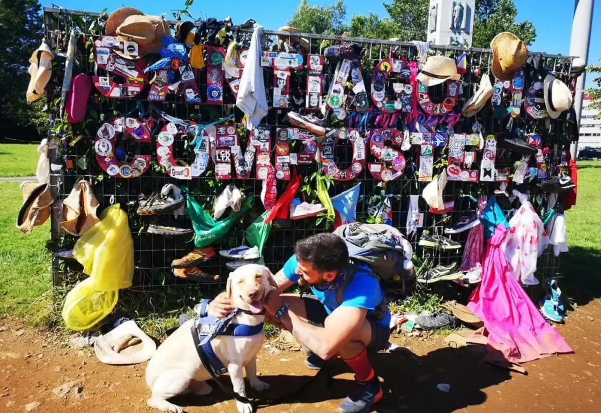 Un peregrino y su perro junto a la entrada de Santiago de Compostela